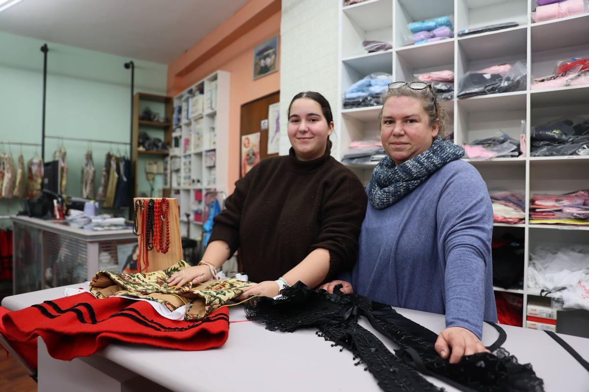 Rosa Paz Martínez y Magdalena Carreño en colocando un traje de asturiana en la tienda J. O. Pepita.