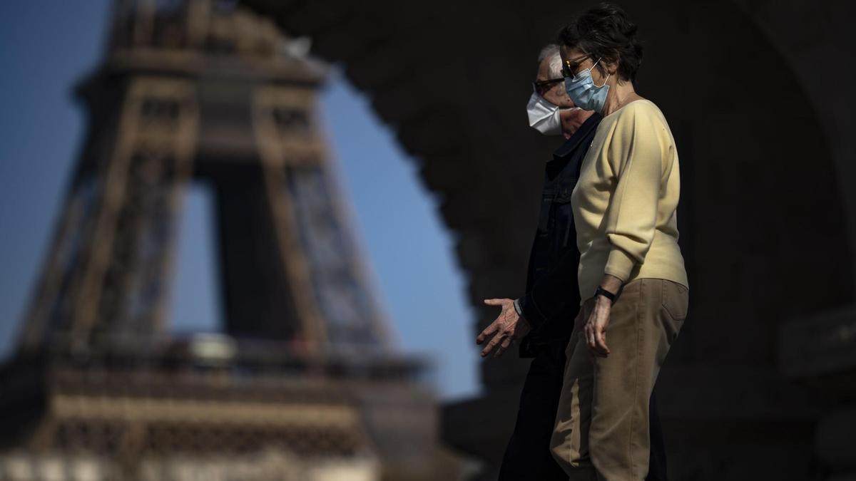 Dos personas caminan frente a la Torre Eiffel con Francia en plena desescalada