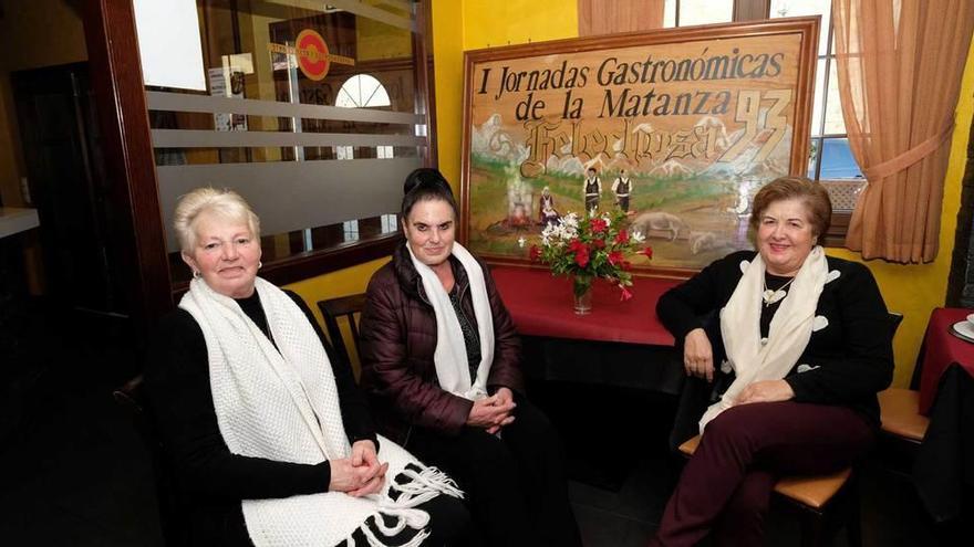 María Fernández, Generosa Tejón y María Luz Alonso, en El Molín d&#039;Eloy, con el cartel de las I Jornadas de la matanza.