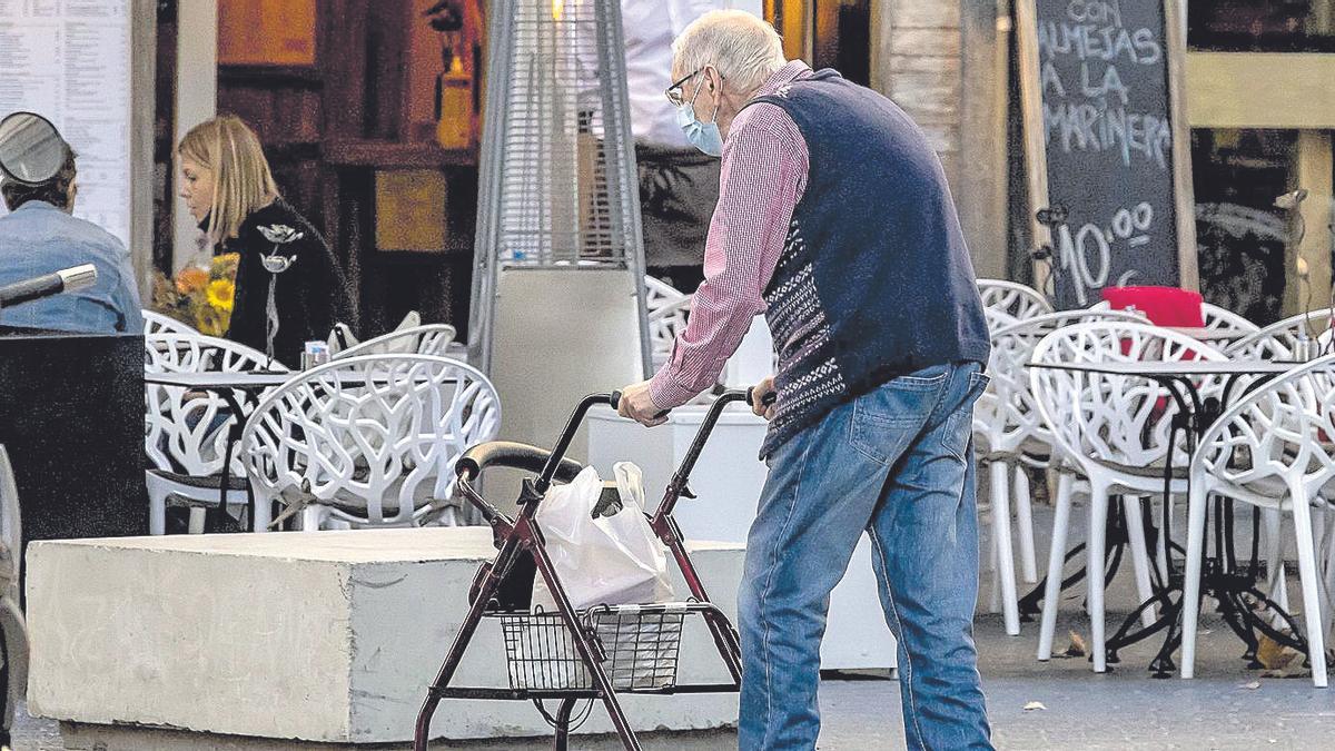 Un hombre mayor camina por la calle con un andador.