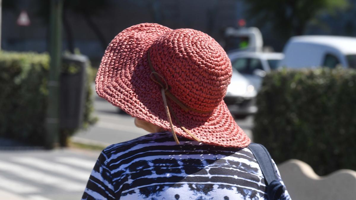 Una mujer se protege del calor con un sombrero.