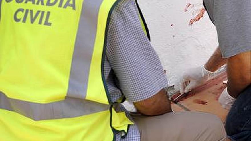 Dos vigilantes de seguridad que trasladaban unas sacas con dinero a un furgón blindado han resultado heridos por los disparos efectuados por un individuo desde una motocicleta, en la localidad sevillana del Viso del Alcor. En la imagen, varios miembros de la Guardia Civil recogen muestras de sangre en el lugar de los hechos.