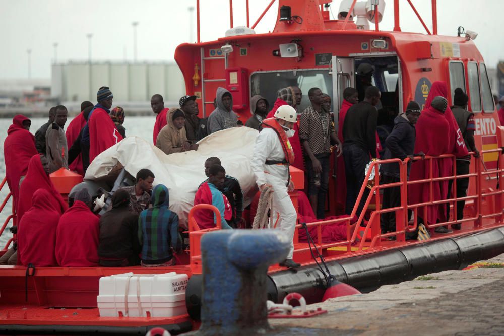 Migrants stand on a rescue boat upon arriving at ...