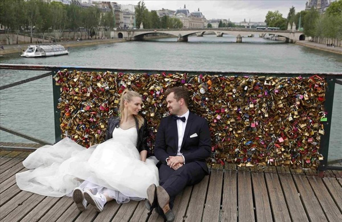Una parella de nuvis asseguts davant una de les baranes plenes de candaus del pont de les Arts, a París, el diumenge 31 de maig. Les autoritats han començat a retirar els candaus l’1 de juny.
