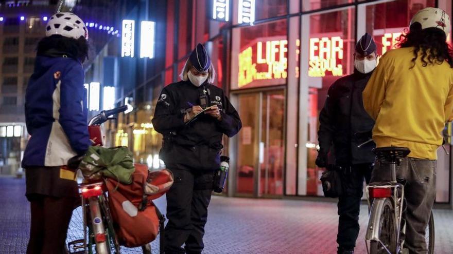 Agentes de la Policía de Bélgica imponen sanciones por violar el toque de queda.