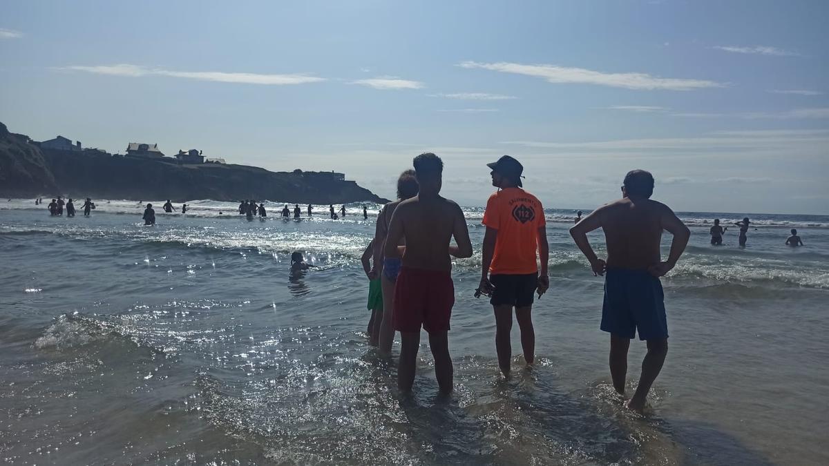 Un socorrista rodeado de bañistas en la playa de Tapia la tarde del jueves.