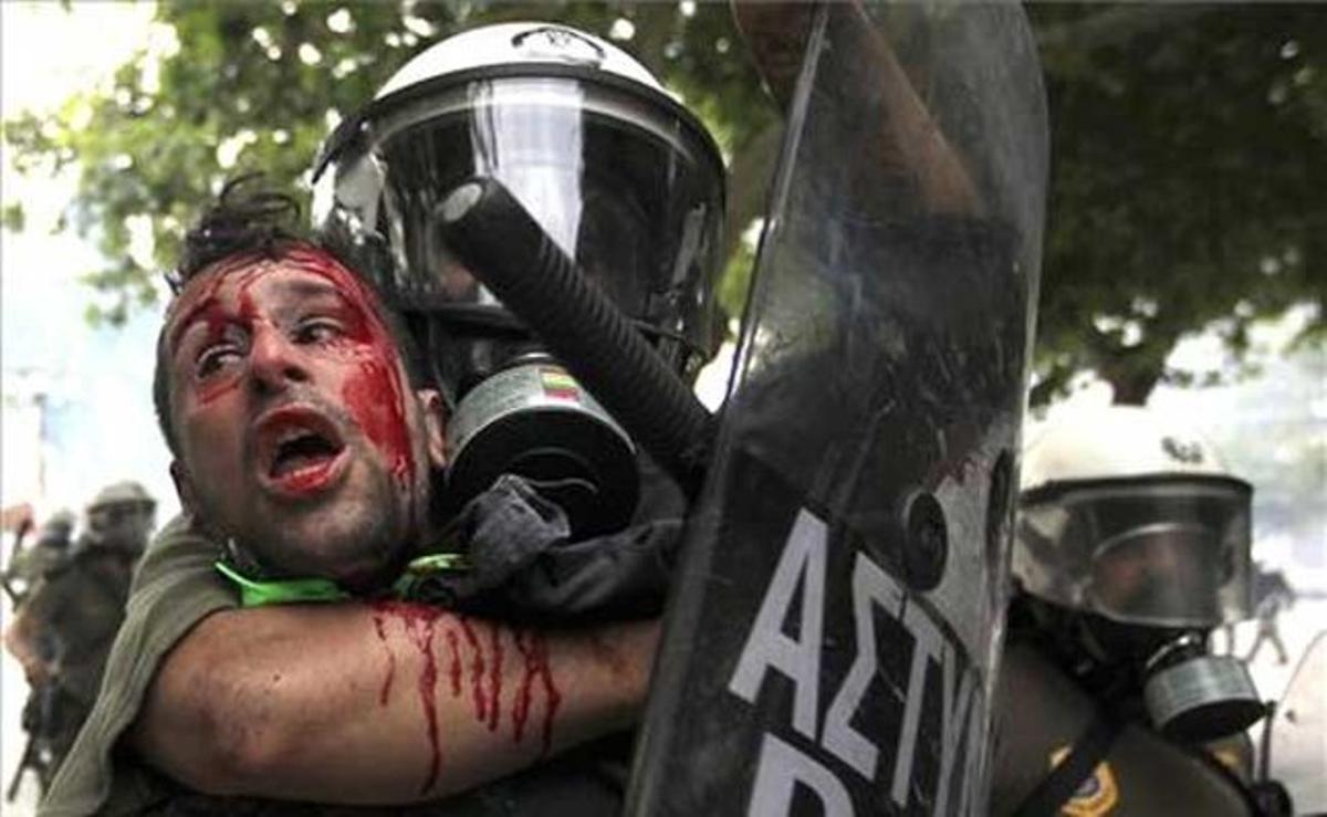 Un manifestant ple de sang és detingut per policies durant les protestes contra el pla d’ajust econòmic.