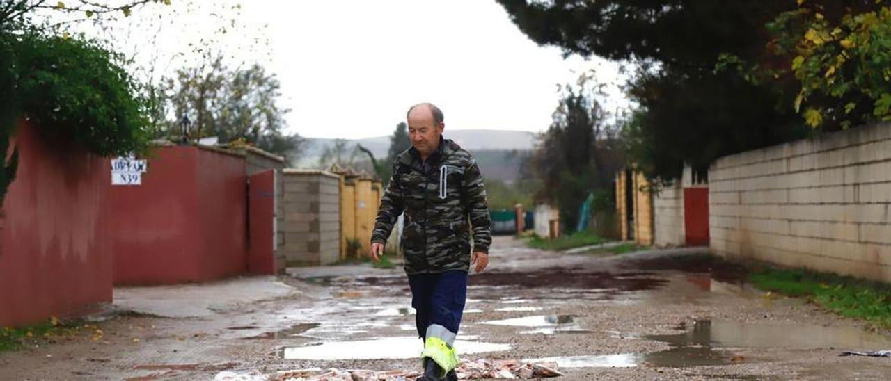 Gabriel, vecino de una parcela en la calle La Tórtola, cubre los socavones convertidos en grandes charcos.