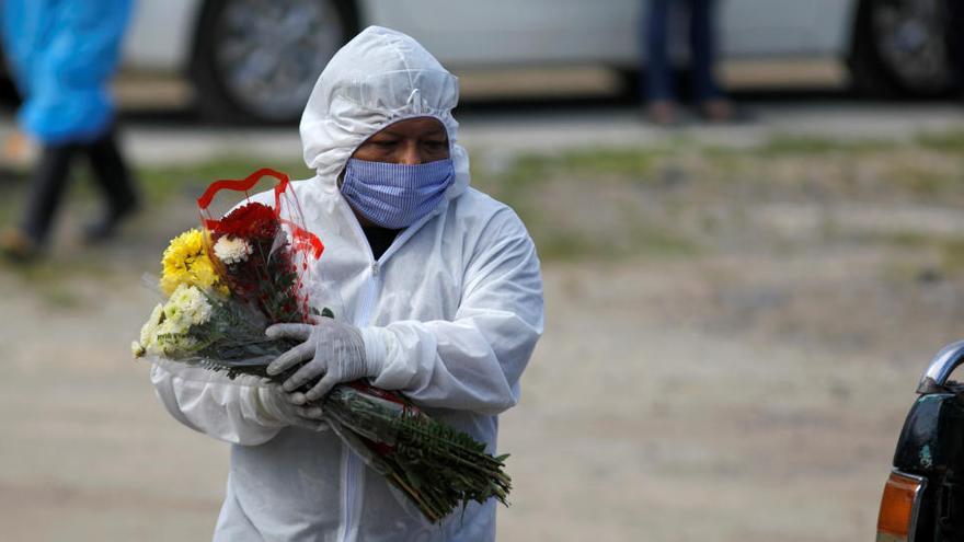Un trabajador de una funeraria lleva unas flores en El Salvador.