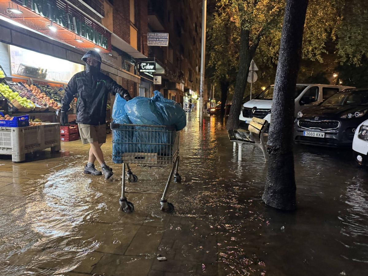 Un vecino trata de mover sus enseres mientras el agua gana altura en Gran Vía Parque.