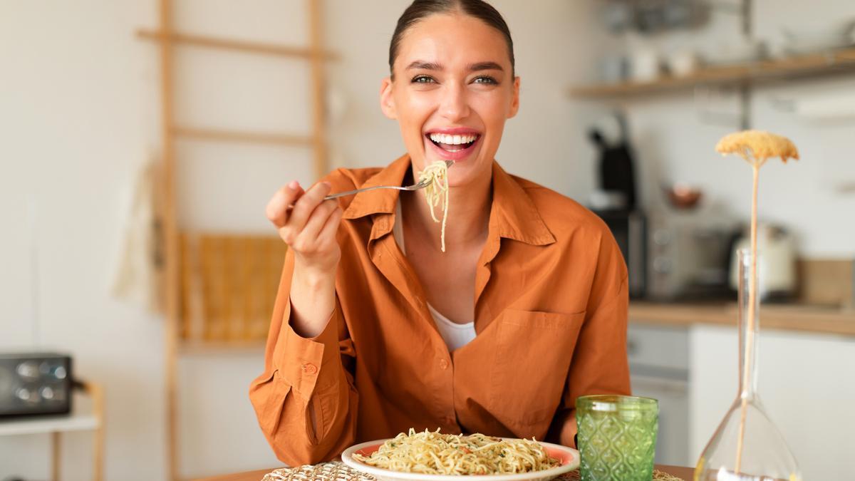 Mujer comiendo pasta en casa