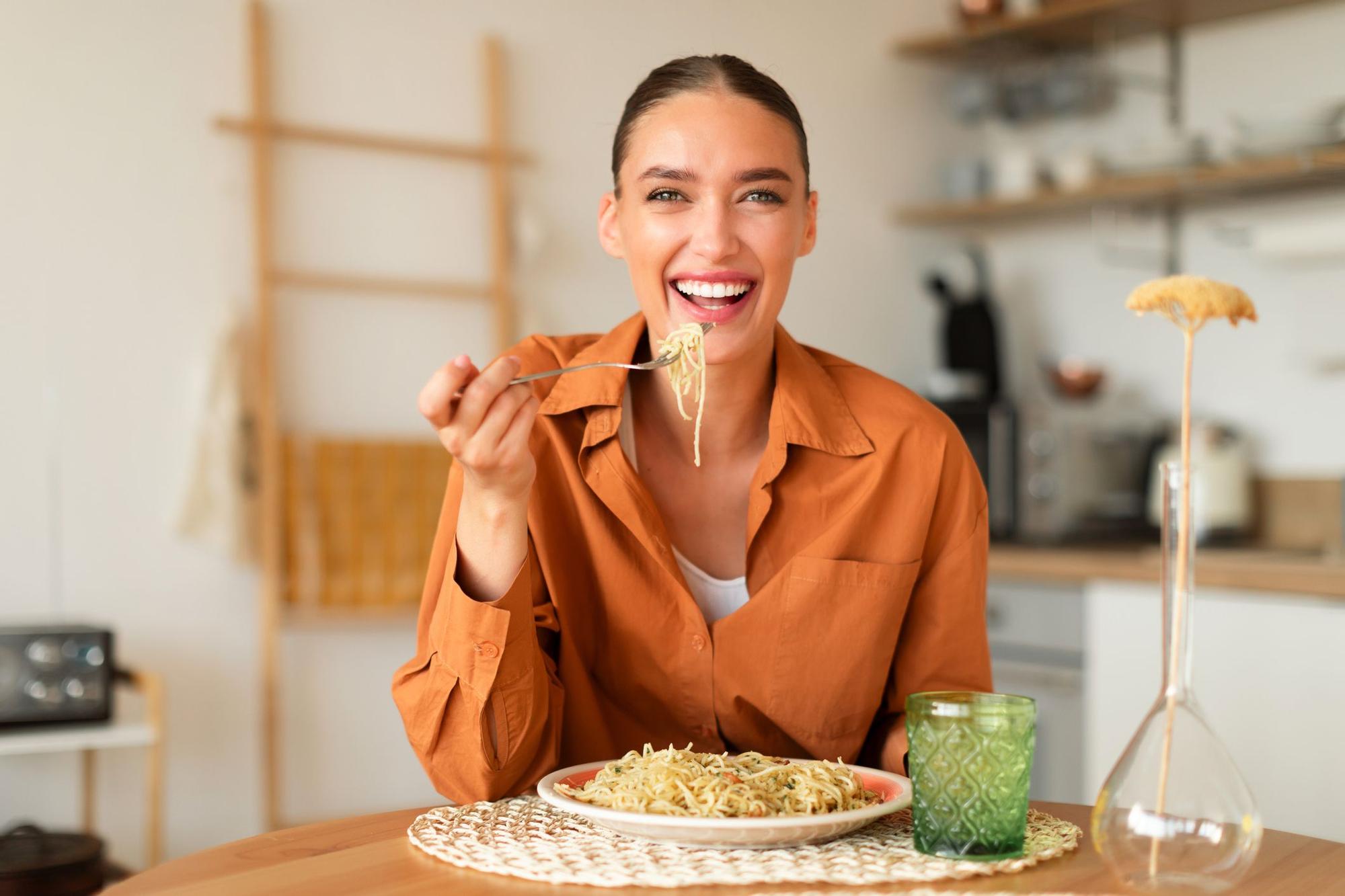Mujer comiendo pasta en casa