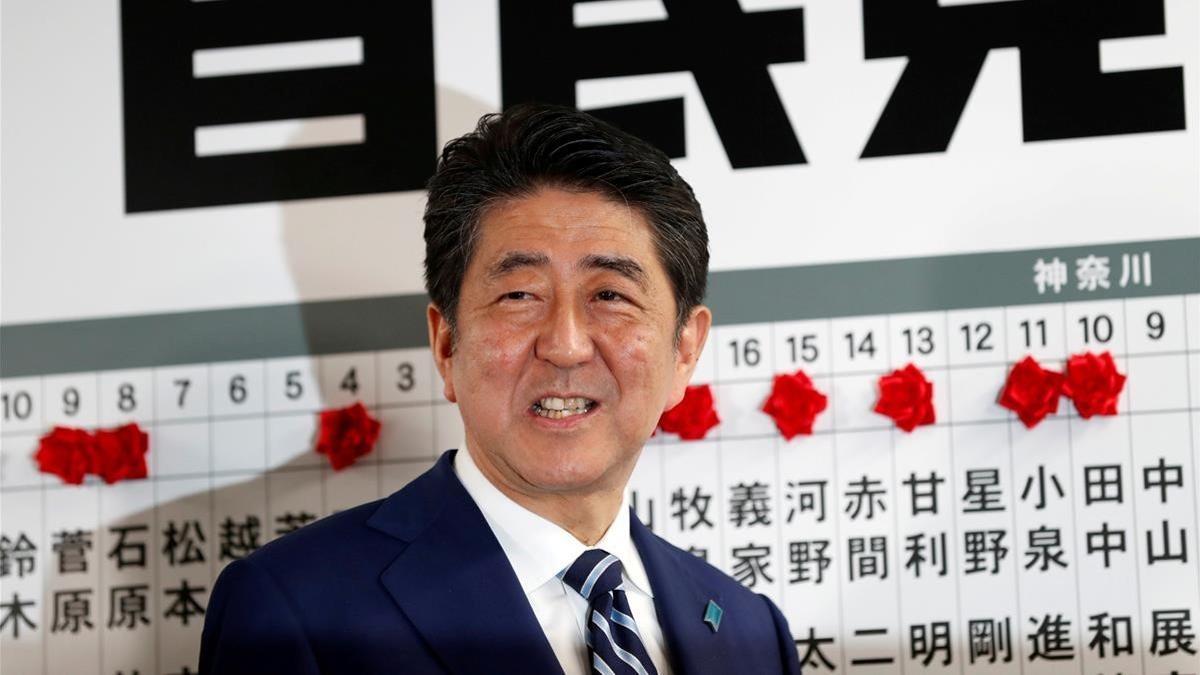 Abe sonríe mientras se dispone a colocar una rosa sobre el nombre de un candidato elegido para la Cámara baja, en la sede de su partido, en Tokio, el 22 de octubre.