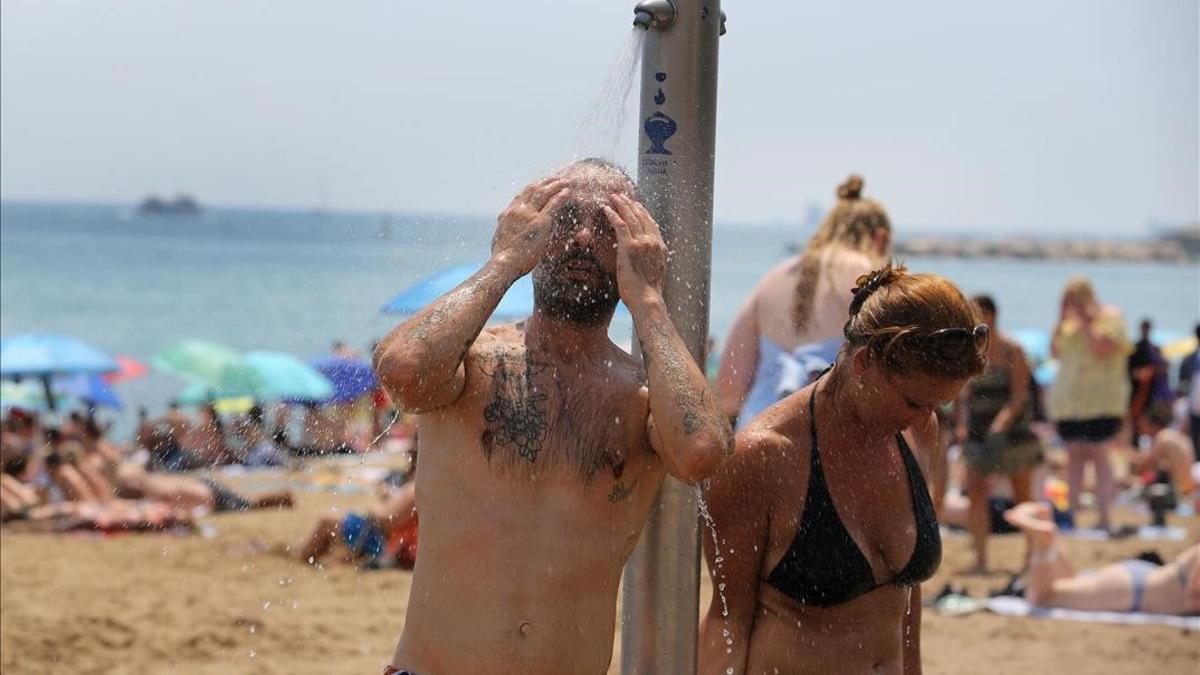 Una pareja se ducha en la playa de la Barceloneta, el verano pasado.