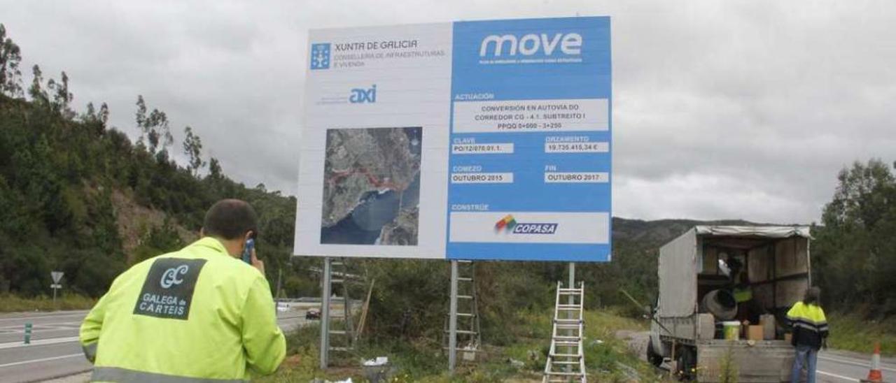 Técnicos instalando el anuncio de la obra del desdoblamiento en San Lorenzo, en Domaio. // S.A.