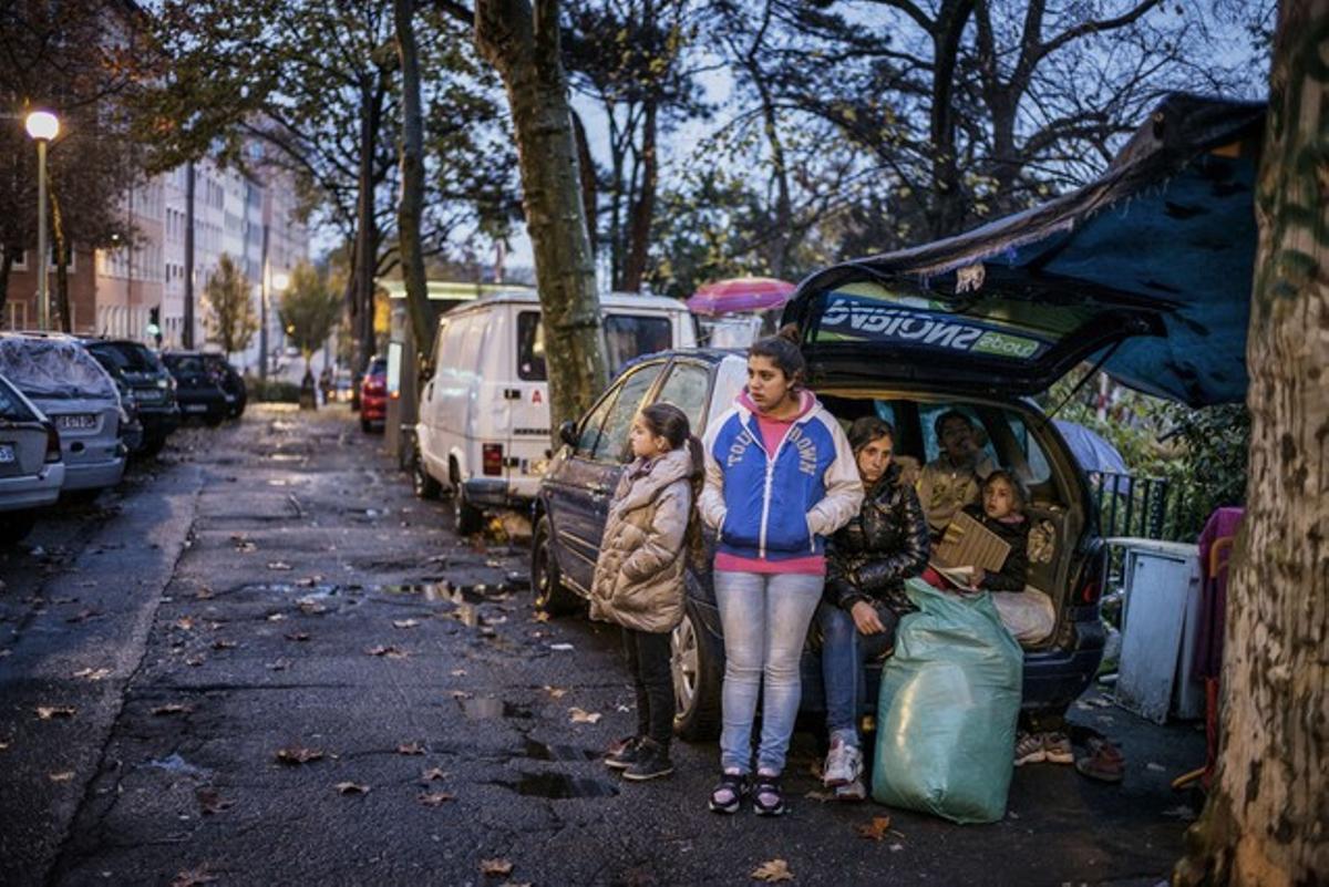 Miembros de familias sin hogar regresan al coche donde viven tras dormir en una escuela ocupada en Lyon.