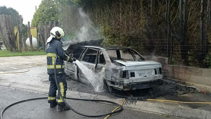 Un bombero apaga las llamas del vehículo, completamente calcinado