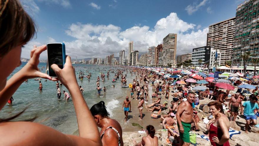 Un turista realizando una foto en agosto en la playa de Levante de Benidorm