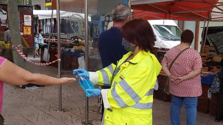 Una agent cívic desinfecta les mans a una persona al mercat de Solsona