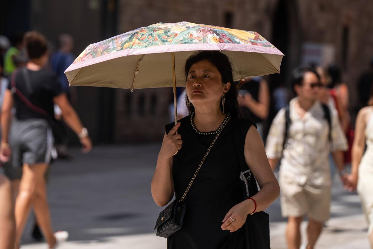 Una mujer sostiene un paraguas para protegerse del sol.
