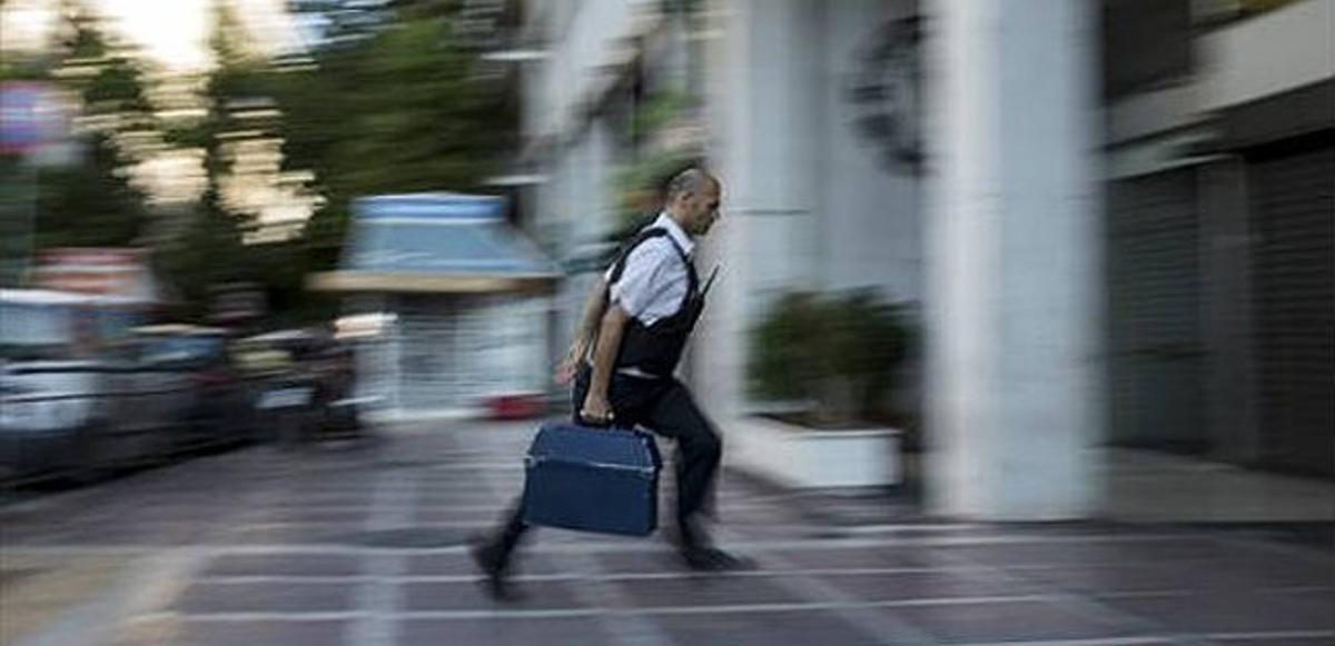 Un home entra diners amb una maleta en una sucursal bancària de la ciutat d’Atenes.