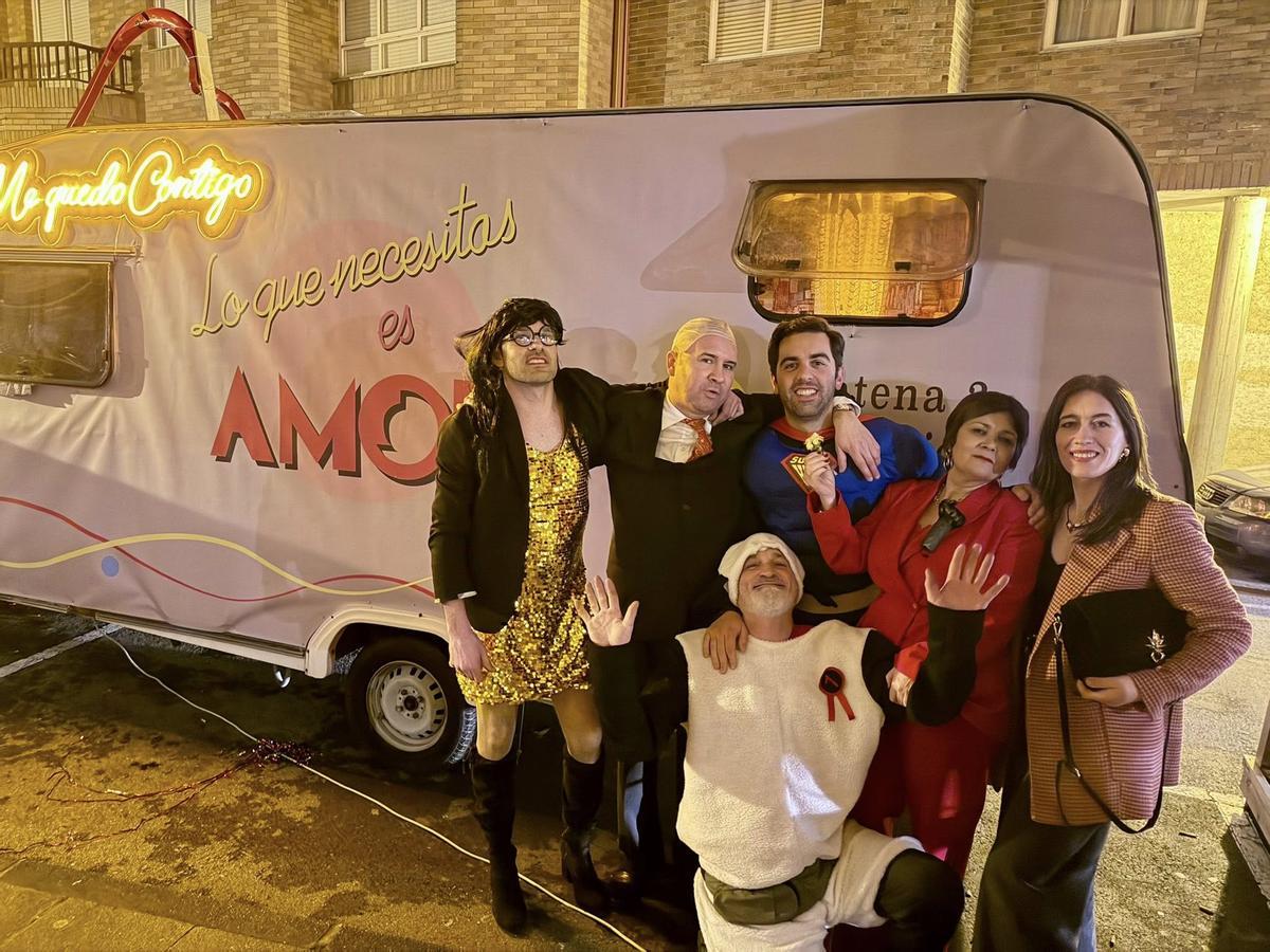 O alcalde de Oroso, Álex Doval, centro, disfrazado de Superman ante unha autocaravana dedicada ao mítico programa de TV 'Lo que necesitas es amor'.