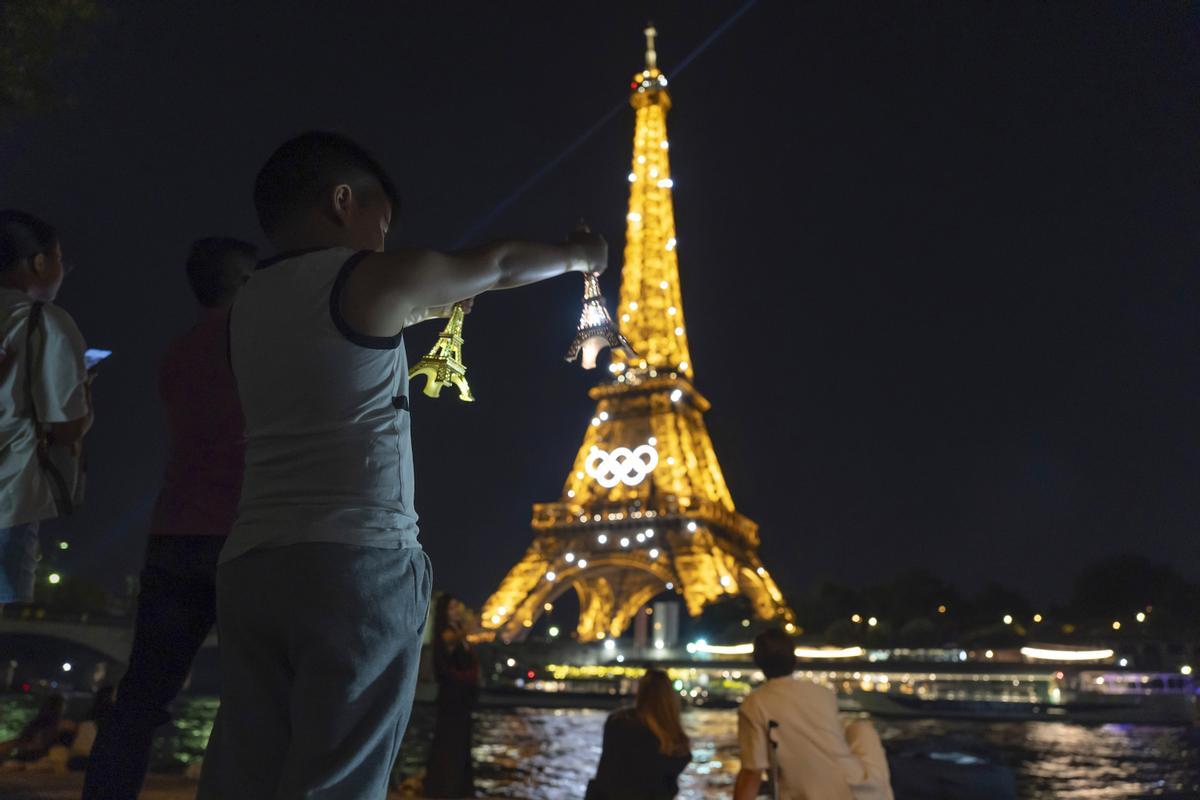 Nick Nguyen, 6, standing with his father, Bay, left, holds his miniature Eiffel Towers while standing in front of the real one decorated with the Olympic rings ahead of the 2024 Summer Olympics, Wednesday, July 17, 2024, in Paris. (AP Photo/David Goldman)