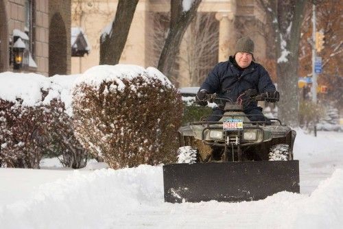 A man plows snow off his sidewalk in Buffalo