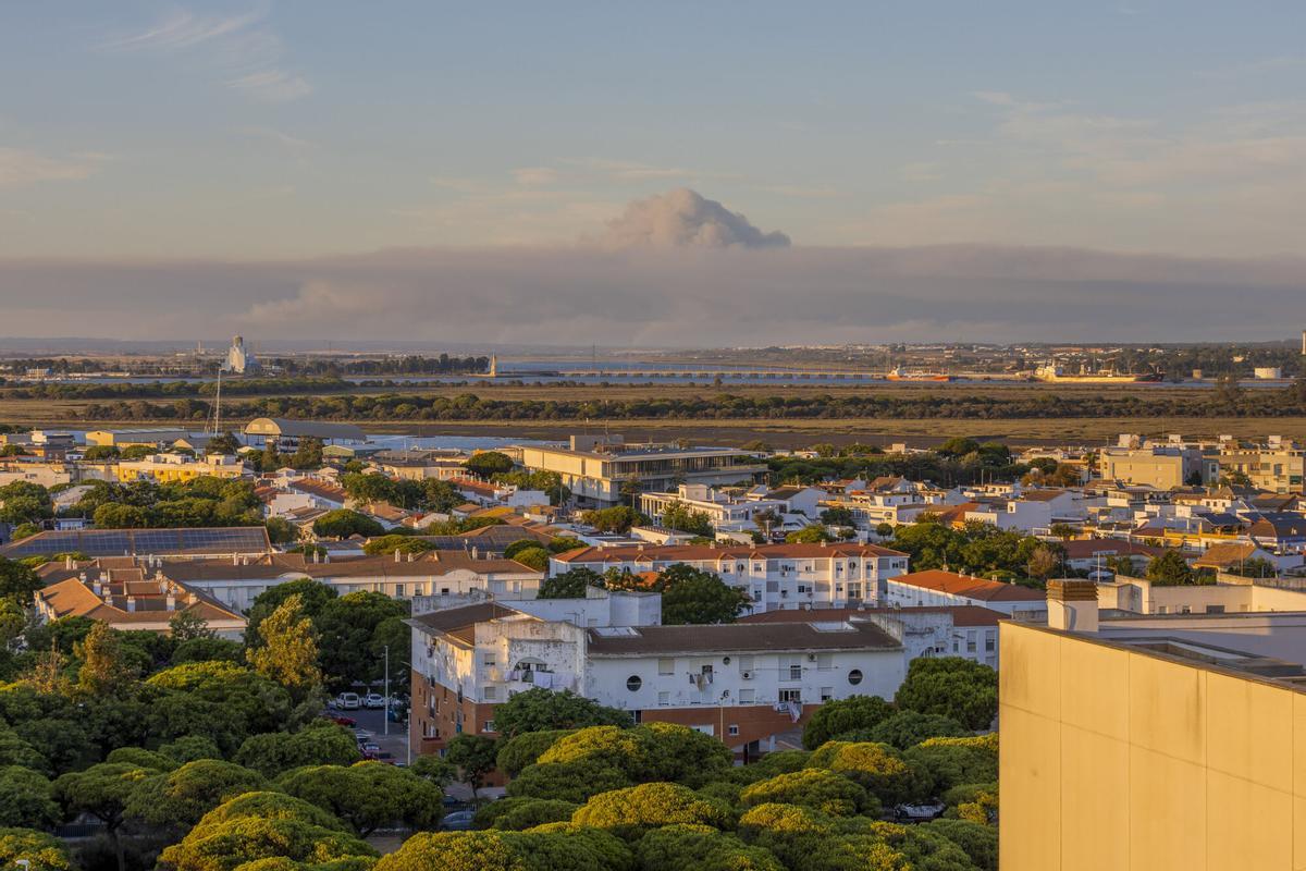Columna de humo del incendio de Niebla visible este domingo desde la localidad costera de Punta Umbría, en Huelva.