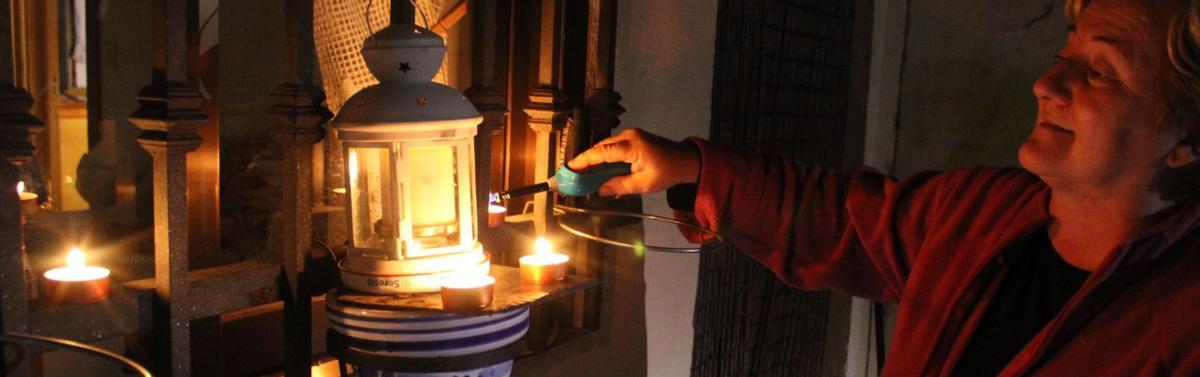 Una vecina prende una vela en un candil en recuerdo de los familiares ya fallecidos, en la noche de la fiesta de Todos los Santos. | A. S.