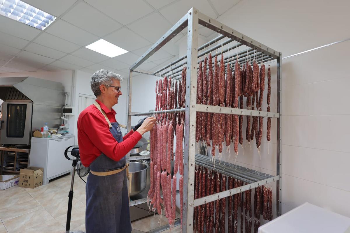 Alfonso Oliver, tercera generación de carniceros, cuelga las longanizas frescas en el secadero.