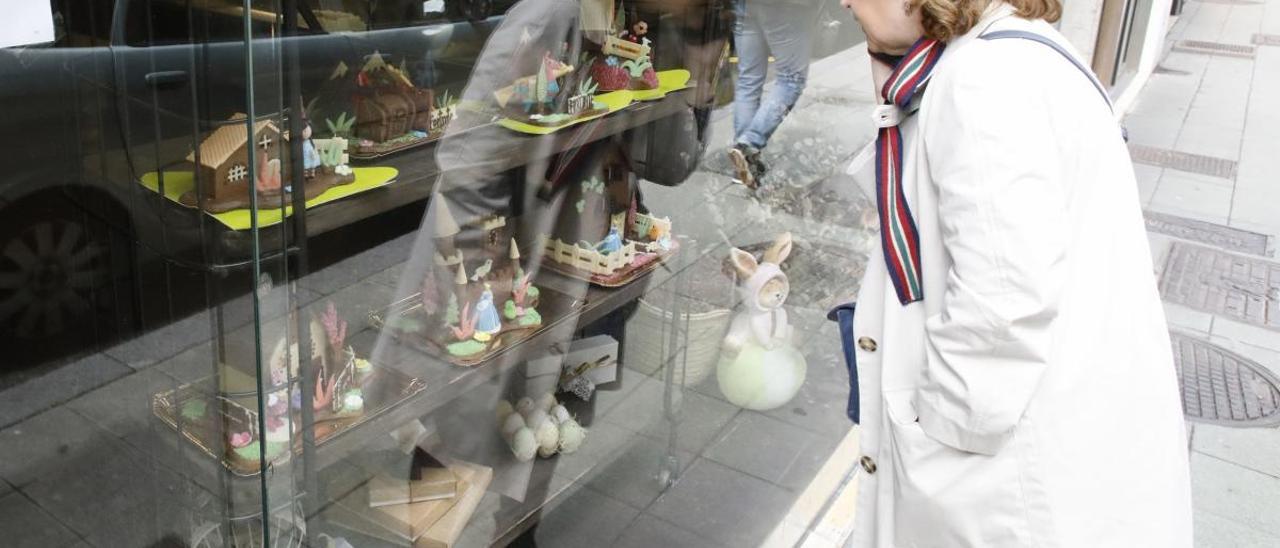 Una mujer, en el escaparate de una pastelería en Gijón