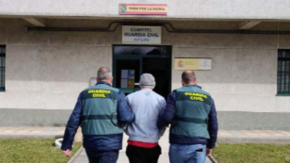 Dos guardias civiles custodian al detenido por al menos once robos en gasolineras de la provincia de A Coruña.