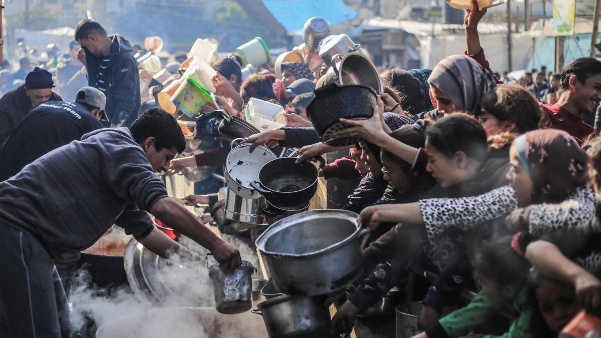 Los palestinos reciben comida preparada en una cocina benéfica en medio de la falta de suministros alimentarios mientras continúan los combates entre Israel y Hamás.