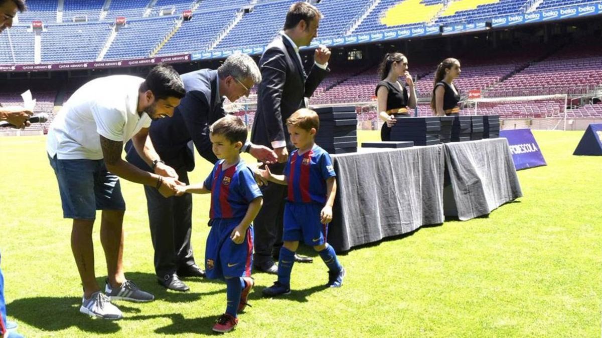 Luis Suárez entrega los premios a los niños de la FCBEscola del Barça en el Camp Nou.