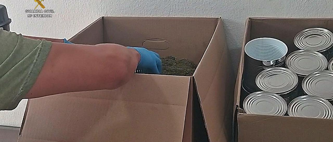 Un agente con marihuana triturada y las latas donde la envasaban al vacío. | INFORMACIÓN