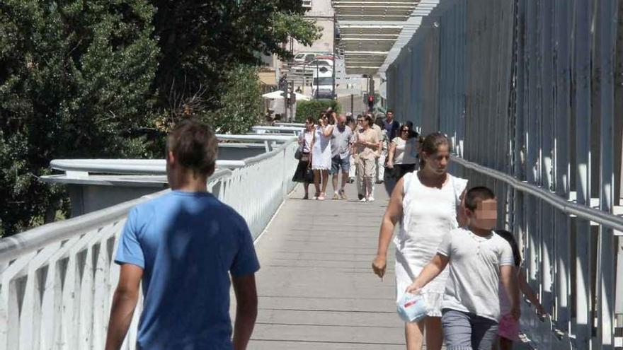 Ciudadanos cruzan el puente por la pasarela.