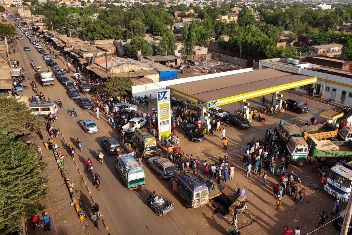Colas de coches, motos y personas con bidones en una gasolinera de Bamako, Malí.