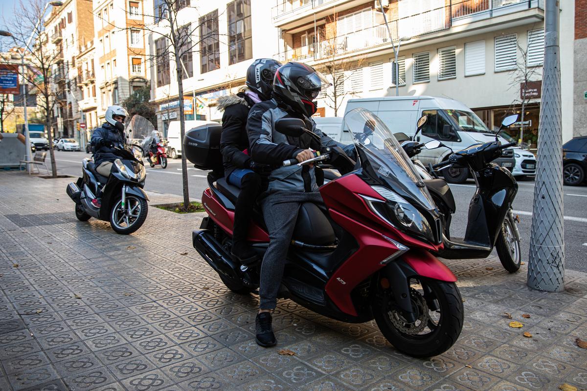 Motoristas sobre la moto, en la acera. La normativa deja claro que, sobre terreno peatonal, hay que bajar y empujar la moto