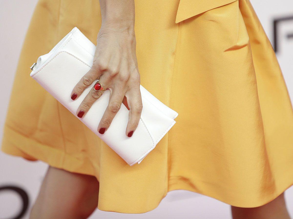 Cartera de mano blanca y anillo rojo del look de Penélope