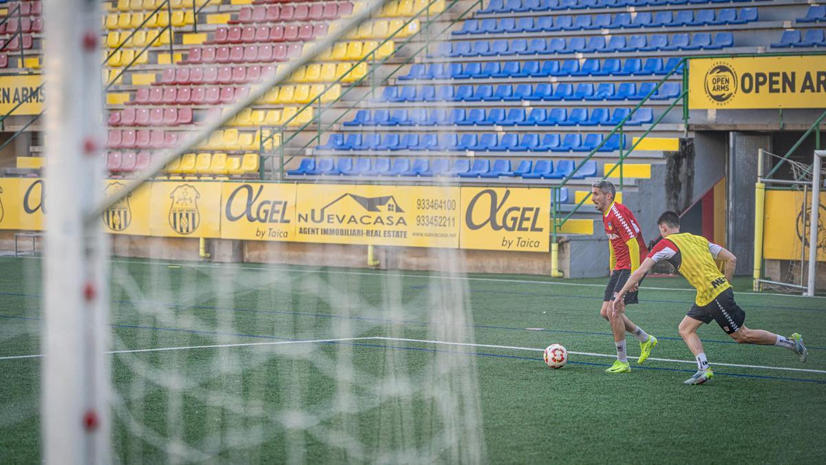 Josu y otro jugador del Sant Andreu, durante un entreno en el estadio Narcís Sala, con parte de la valla pendiente de sustituir al fondo.