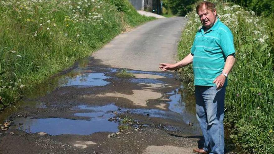 El vecino Aurelio Fernández muestra los grandes baches del pavimento. // Bernabé/Víctor Espiño