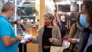 Una mujer con mascarilla valida su entrada en los cines Renoir de Barcelona.