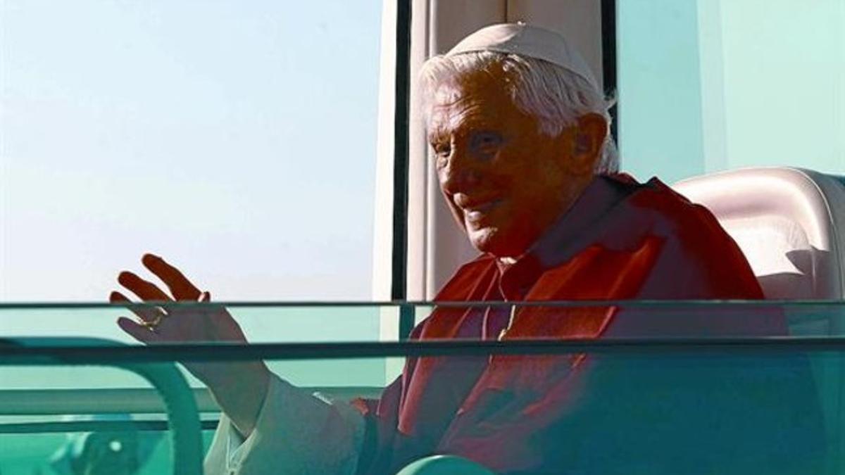 Benedicto XVI saluda desde el 'papamóvil', ayer al llegar a Cuatro Vientos, antes de la misa.