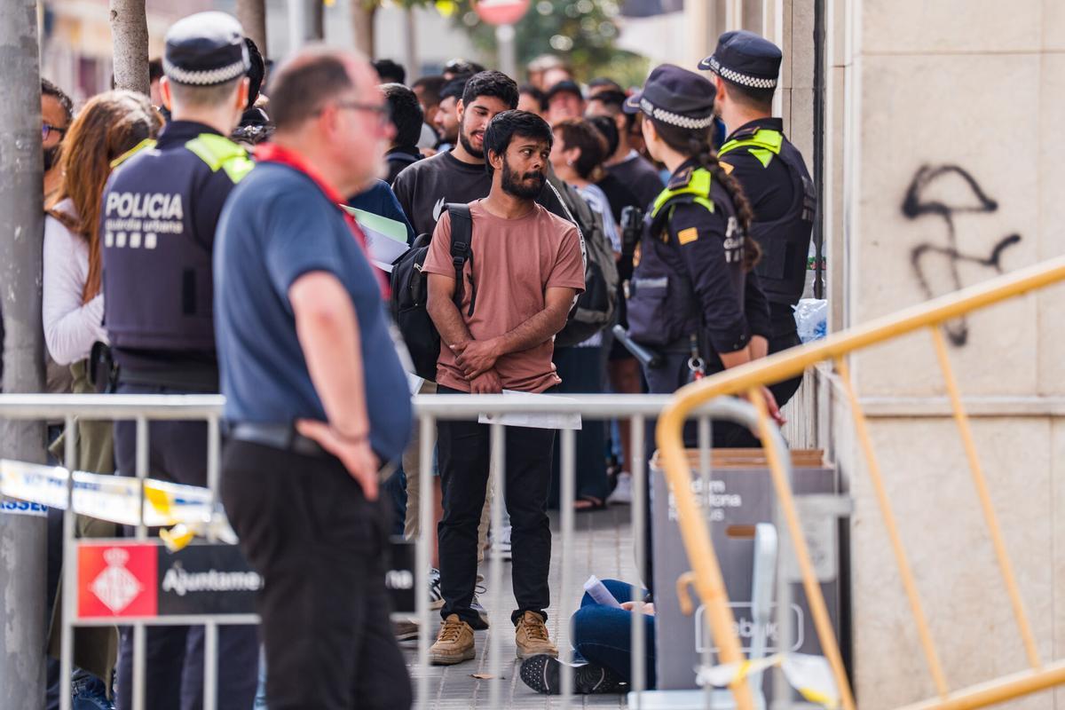 Caos y una larga cola de personas que esperan regularizar su situación en España en la Oficina de Benestar Social i Família de Barcelona-Sants/Eixample.