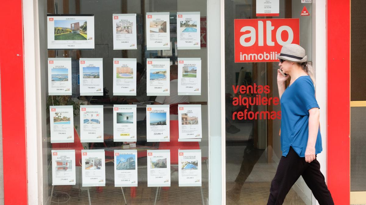 Una mujer pasa por delante de un escaparate de una inmobiliaria alicantina.