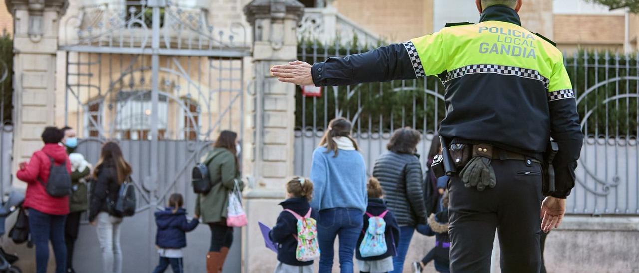 Un agente de la Policía Local controla el tráfico a la salida de un centro de infantil y primaria de GAndia. | ÀLEX OLTRA