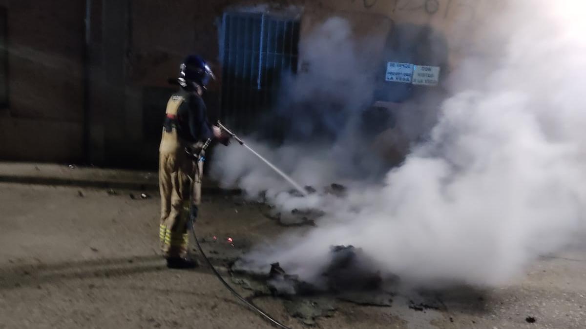 Un bombero apaga uno de los contenedores incendiados la pasada noche en Toro.