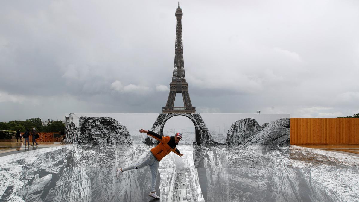 Un hombre posa en una instalación artística gigante colocada ante la torre Eiffel.