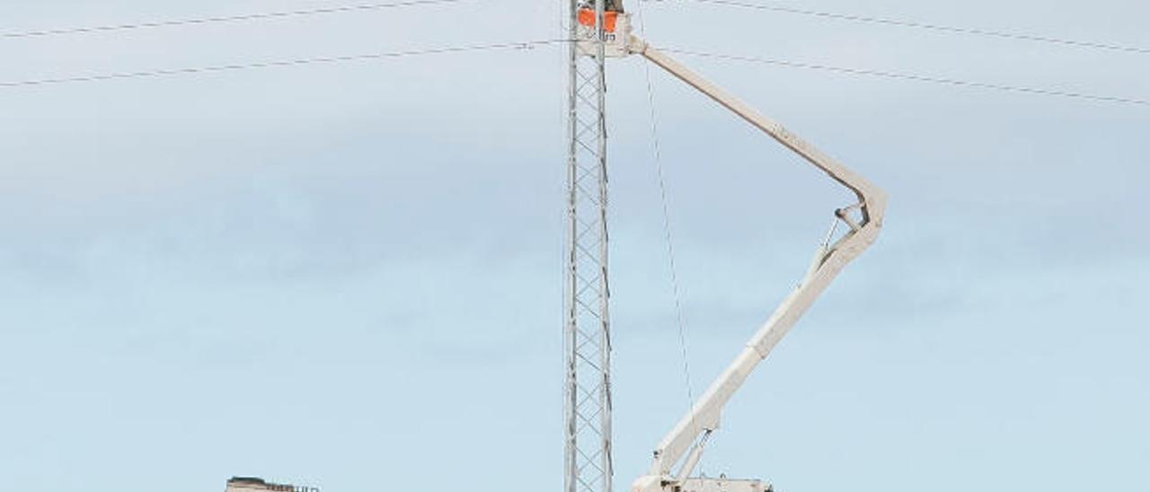 Un grupo de operarios trabajan en una torre de alta tensión en Antigua.